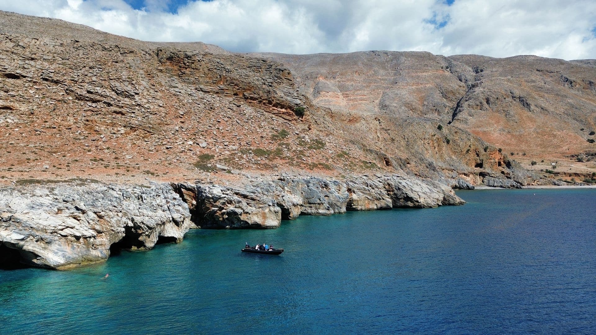 Boat beneath the cliffs of Crete's wild southern coast