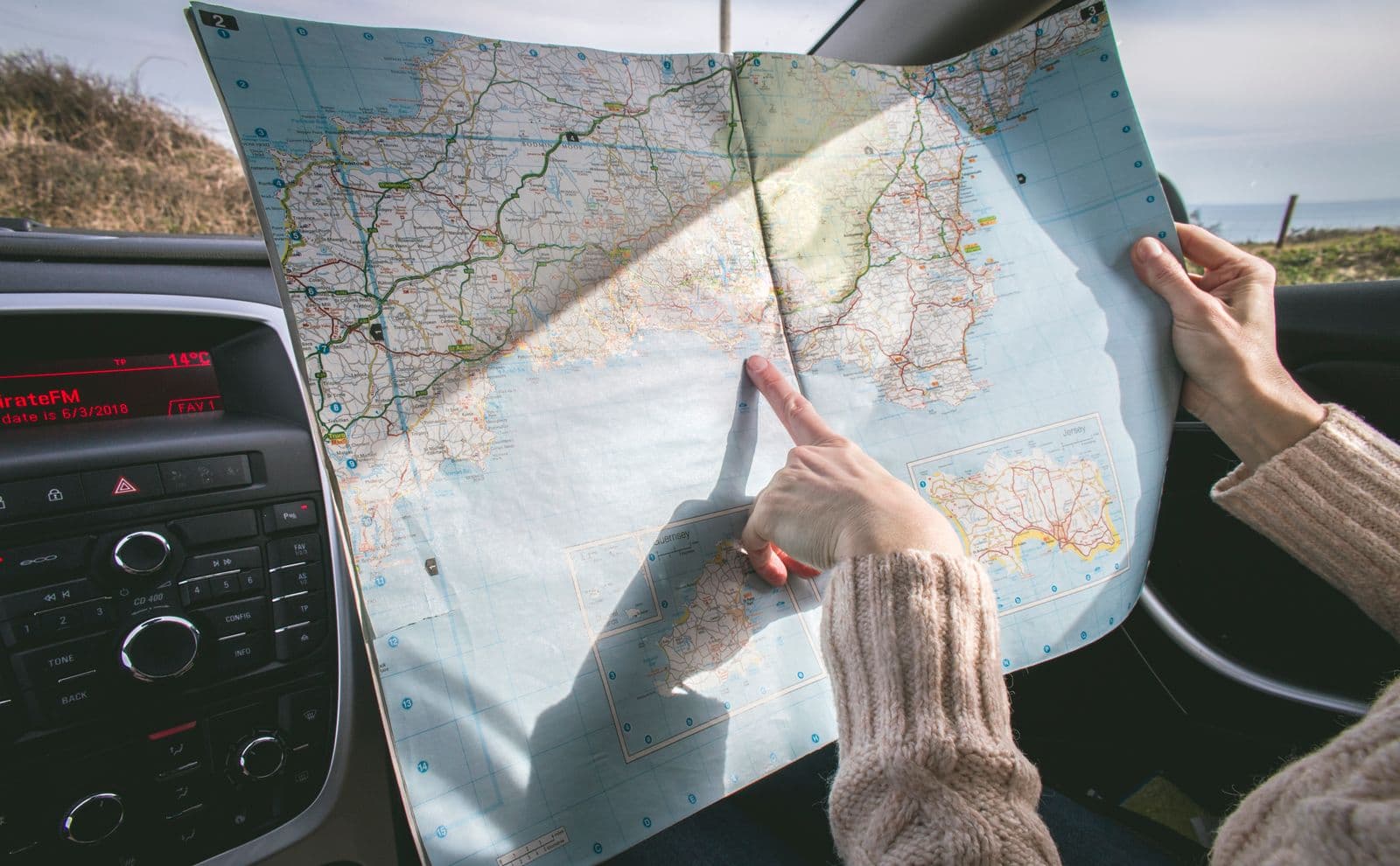 Reading a road map inside a car by the Cretan coast